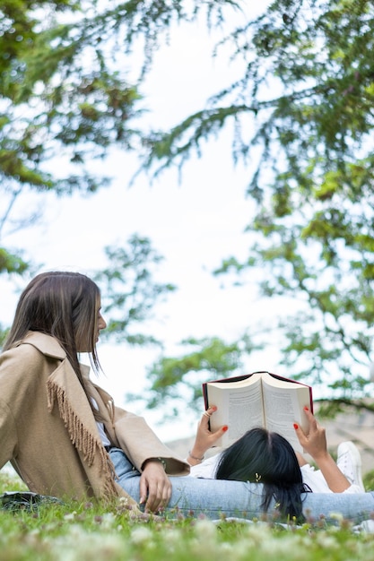 Two friends enjoying a day together in the park while getting some fresh air and reading a book