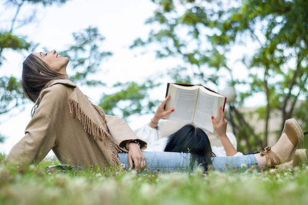 Two friends enjoying a day together in the park while getting some fresh air and reading a book