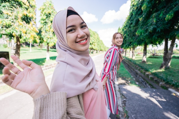 Two friends enjoying the summer sun and holding hand walking in the park