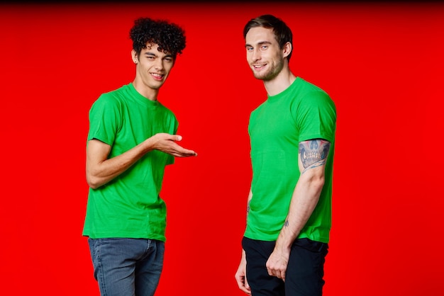 Two friends in green tshirts fun communication red background