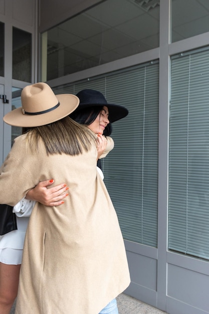 Two friends greeting each other with a hug at the entrance of a building