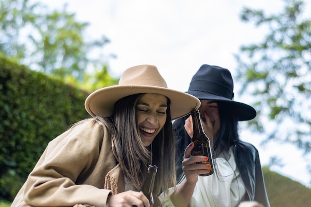 Two friends having a good time drinking beer and laughing in the park