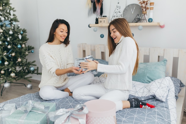 Two friends open Christmas gifts.