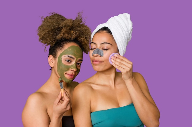 Two friends pamper themselves with facial treatments for a relaxing spa day at home