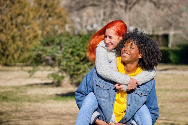 Two friends on a piggyback riding one on top of the other one white with orange hair and the other black with afro hair