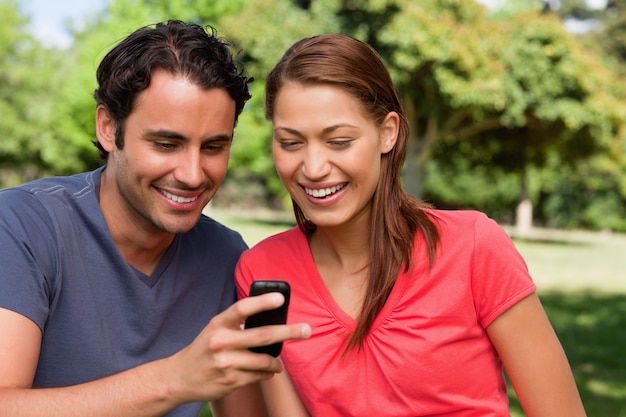 Two friends smiling as they are looking at something on a mobile phone