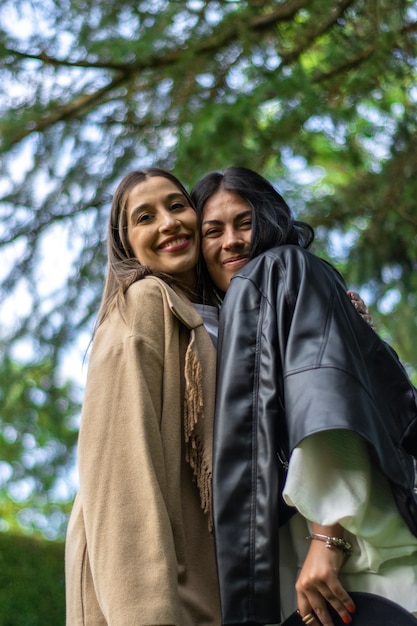 Two friends together happily looking at the camera with tree branches behind them