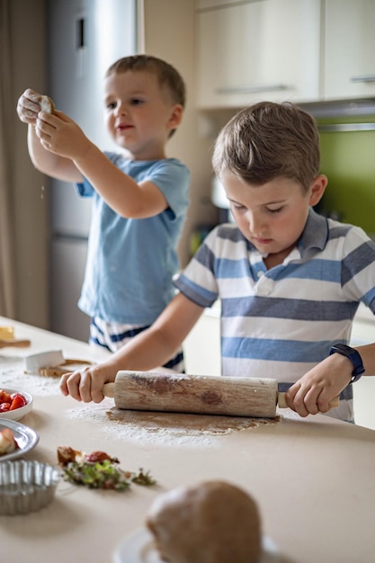 Two funny brothers cooking homemade summer dessert preparing dough and slicing ingredients