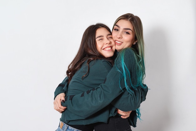 Two funny happy women girl friends embrace on white background. women's friendship, sisters, youth