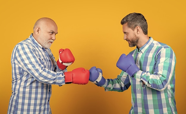 Photo two generation men boxing isolated on yellow generation men boxing in studio