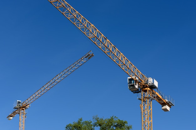 Two generic construction cranes on a blue sky background