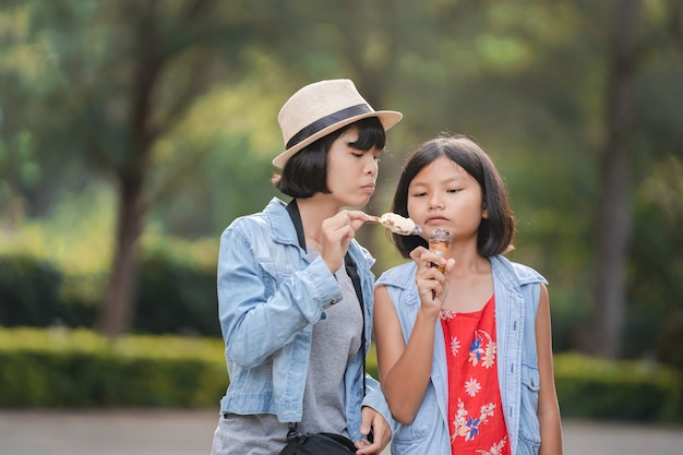 Two girl eating ice cream on street during walking travel at park