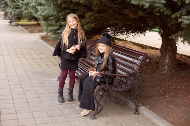 two girl friends are sitting on a park bench with cocoa in their hands, chatting sweetly