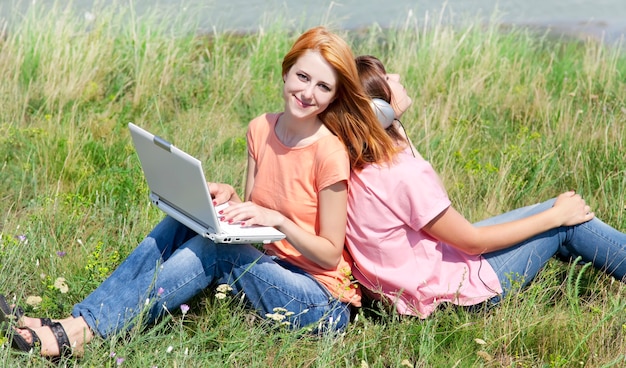 Two girlfriends at countryside with laptop and computer.