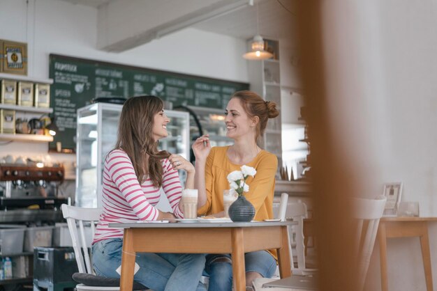 Photo two girlfriends meeting in a coffee shop talking