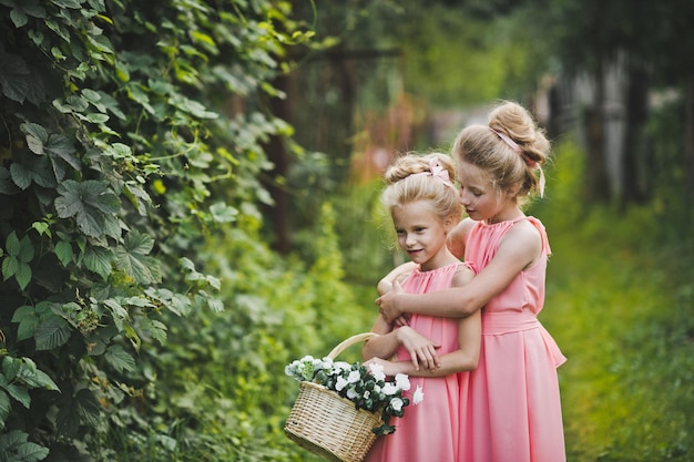 Two girlfriends in a pink dress playing in the garden amongst the greenery 6592