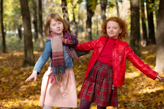 Two girlfriends run through the autumn park Children play in autumn