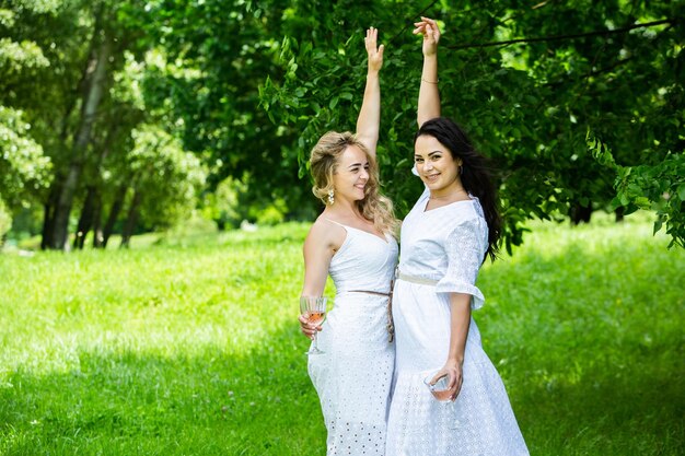 Two girls are resting in park sitting on a picnic blanket Friends is making picnic outdoor