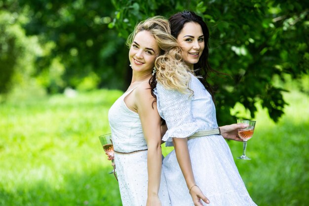 Two girls are resting in park sitting on a picnic blanket Friends is making picnic outdoor