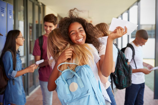 Two girls celebrating exam results in school corridor