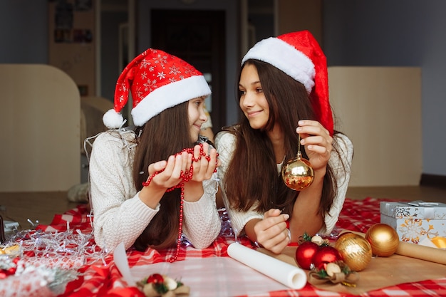 Two girls in christmas hats packing christmas gifts