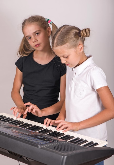 Two girls playing piano Kids play music Classical education for children art lesson Little girl at digital keyboard Instrument for young student Music class in school or at home