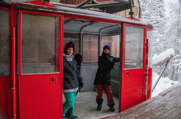 Two girls in the red skilift cabine in the strong snowfall in the mountains of the Caucasus