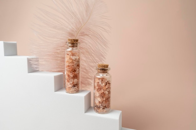 Two glass bottles with pink salt for spa procedures standing on a white stairs