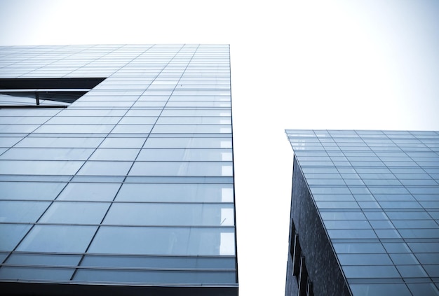 Two glass buildings are seen from the ground, one of which is blue.