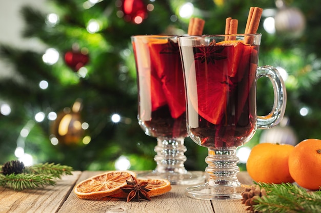 Two glass of christmas mulled wine or gluhwein with spices and orange slices on rustic table against...