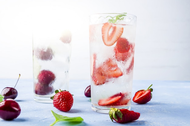 Two glass of refreshing cool detox drink with strawberry, cherry and mint