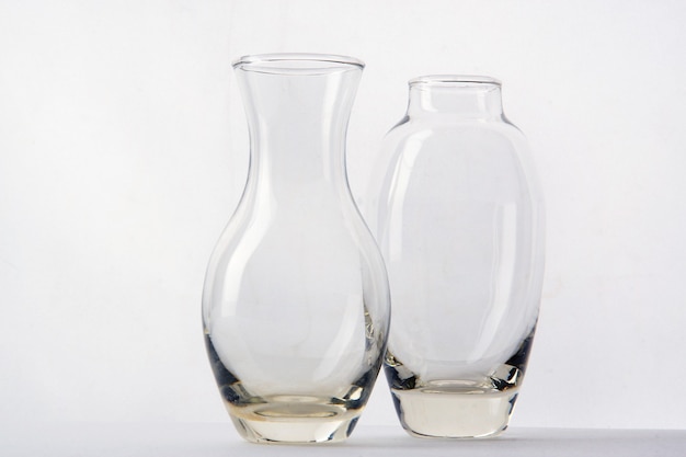 Two glass vases of different shapes are side by side on a white background