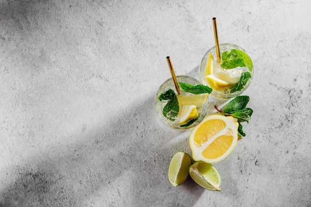 Two glass with lemonade or mojito cocktail. Summer drinks with fresh citrus and ice.