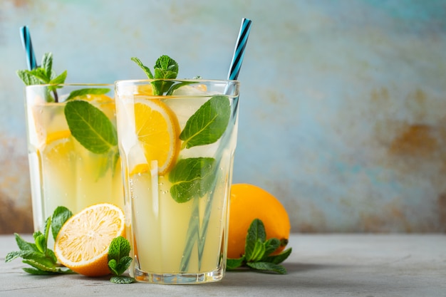 Two glass with lemonade or mojito cocktail with lemon and mint, cold refreshing drink or beverage 