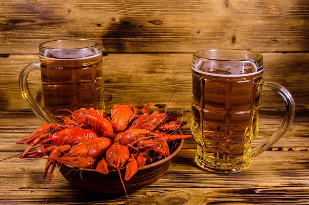 Two glasses of beer and boiled crayfish on wooden table