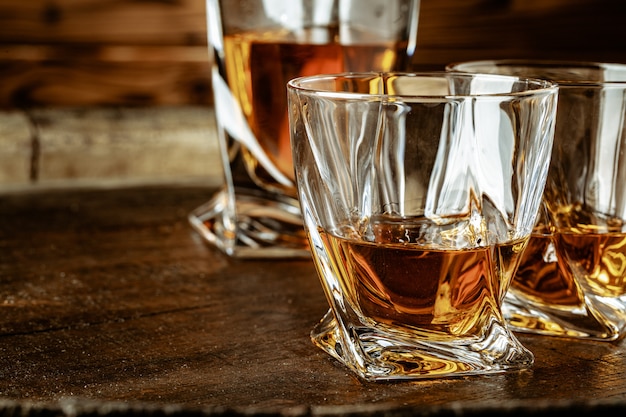 Two glasses of brandy or cognac and bottle on the wooden table