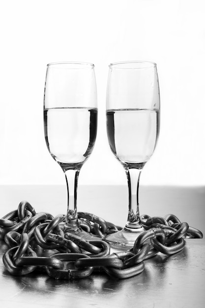 Two glasses in chains as a symbol of dependence.