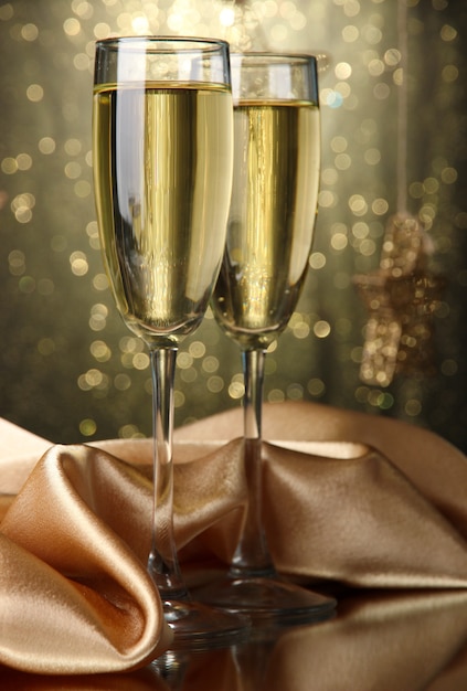 Two glasses of champagne on bright background with lights