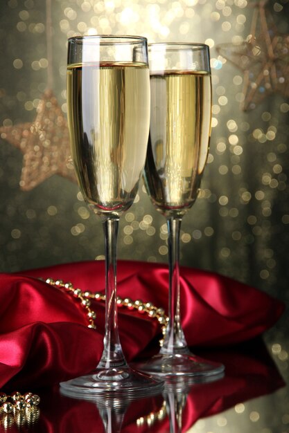 Two glasses of champagne on bright background with lights