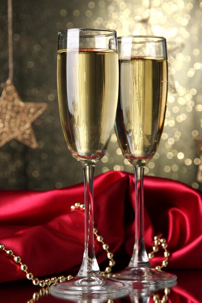 Two glasses of champagne on bright background with lights