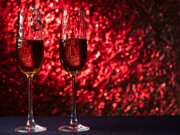 Two glasses of champagne stand on a blue surface with each other on a pink