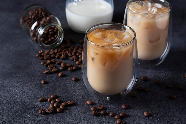 Two glasses of cold coffee with milk and ice cubes on a dark background Closeup