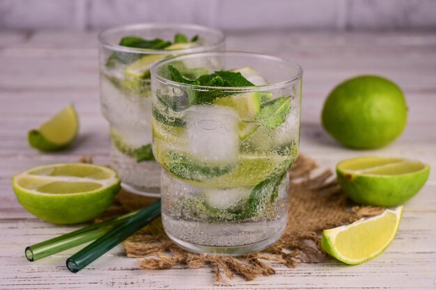 Two glasses of gin with limes and a lime on the side