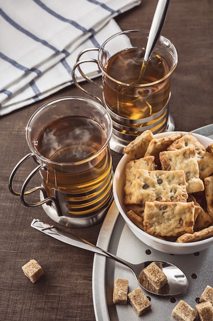 Two glasses of hot tea napkins and spoons on a wooden table Brown sugar lumps