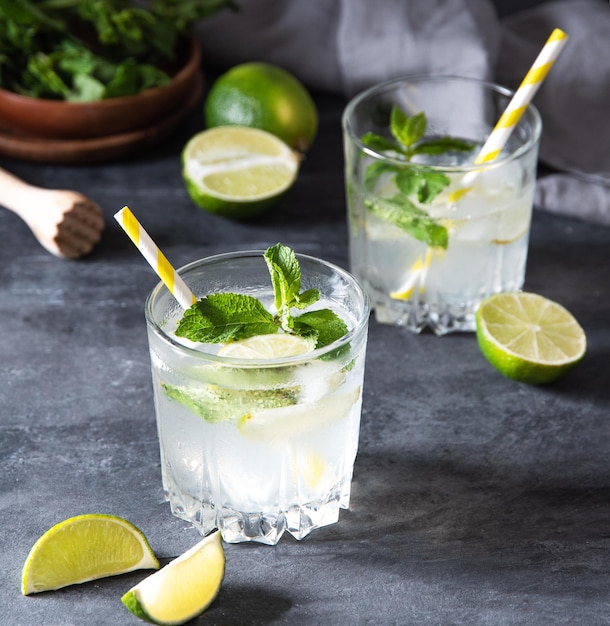 Two glasses of lime lemonade mojito with lime slices and mint on gray background . dark photo. Macro and close up image