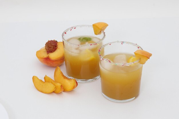 Two glasses of peach margaritas with a peach slice on the rim.