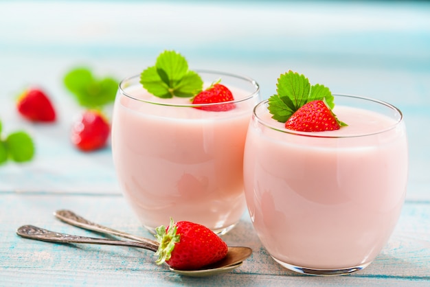 Two glasses of pink yogurt on wood