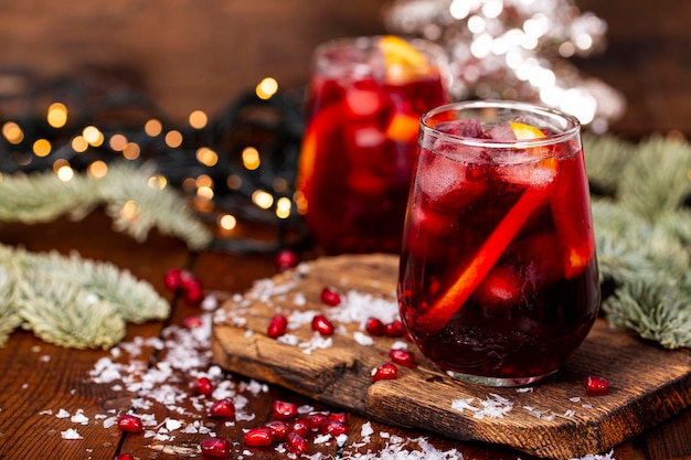 Two glasses of pomegranate cocktail with orange on the background of christmas decorations and