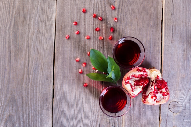 Two glasses of pomegranate juice and ripe pomegranate on a wooden background. Healthy drink concept