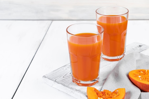 Two glasses of pumpkin juice on white wooden background Vegetable detox drink for healthy diet